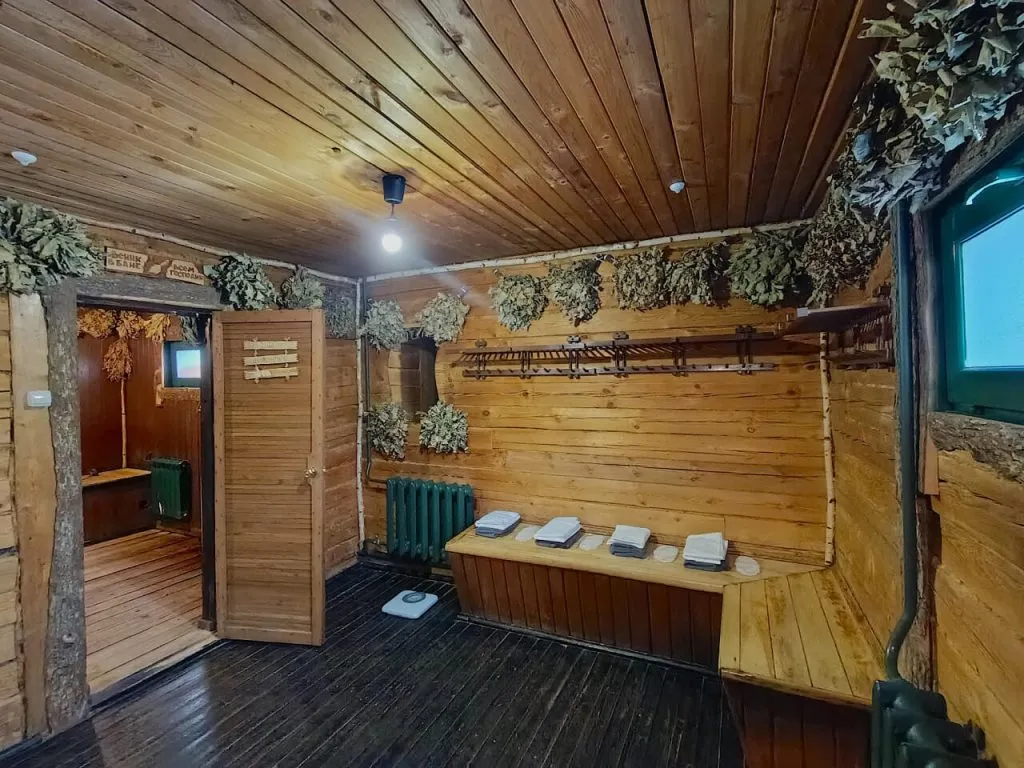 Русская баня внутри, деревянные стены, уютное оформление, банное оборудование, светлый интерьер, элементы декора, территория в Подмосковье, отдых, здоровье, релаксация, природа, акцент на комфорт.